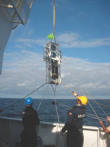 Figure 2: The benthic lander Audacia is raised over the side for deployment by the deck crew of the modern Chilean scientific vessel Cabo de Hornos, operated by the Chilean Armada. The glass spheres put bouyancy high, while the instruments put the weight low, creating inherent stability. (Image: Courtesy Kevin Hardy and Atacamex 2018)