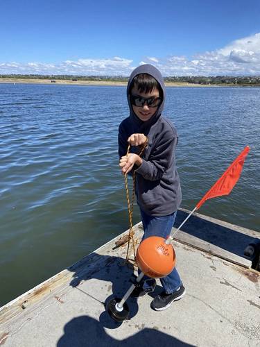 Figure 1.  Sawyer Granados, a fourth grader in San Diego, California, hauls in his STEM Lander after a successful dive to 15-ft in Mission Bay.  His STEM Lander has yet to dive the blue Pacific Ocean. The pre-publication boat trip was scrubbed by high surf.  Something to learn there, too.  (Photo: Kevin Hardy)